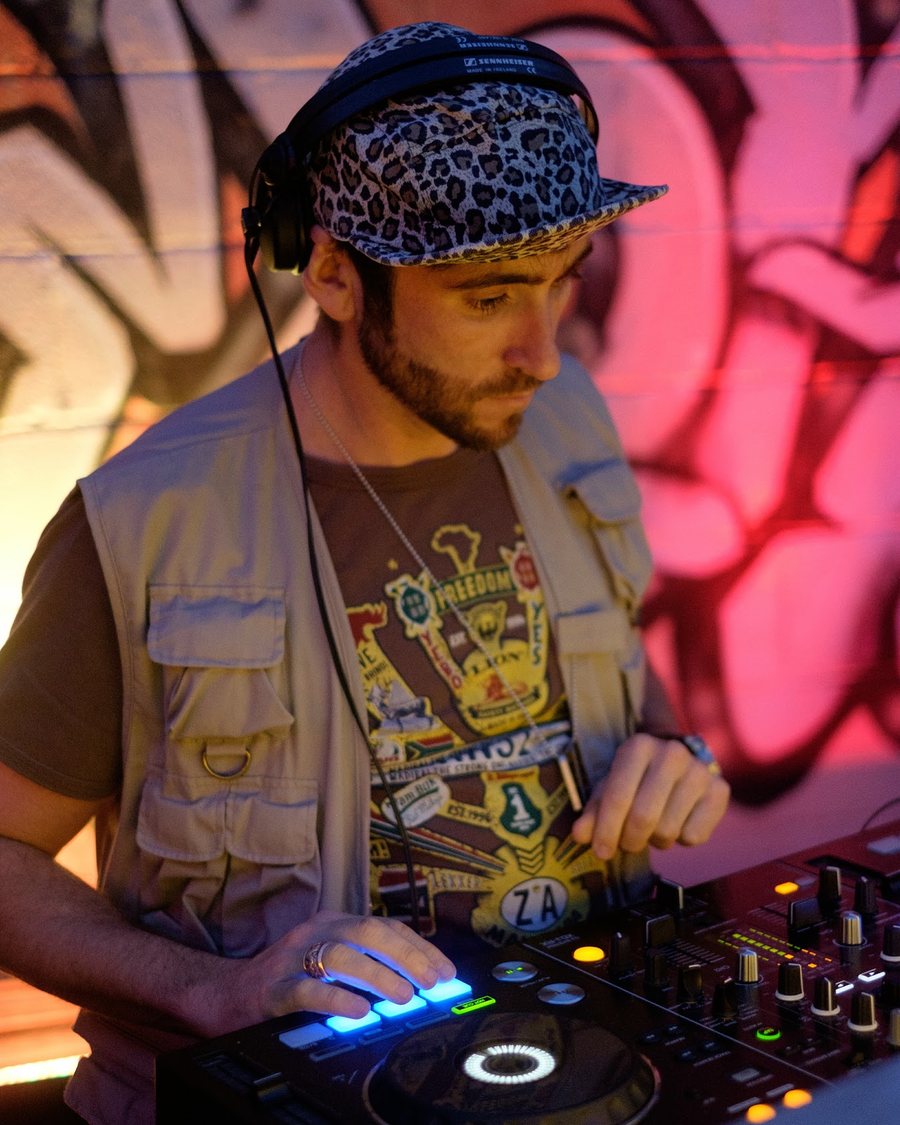 Josh DJing on Pioneer decks in front of a graffiti wall