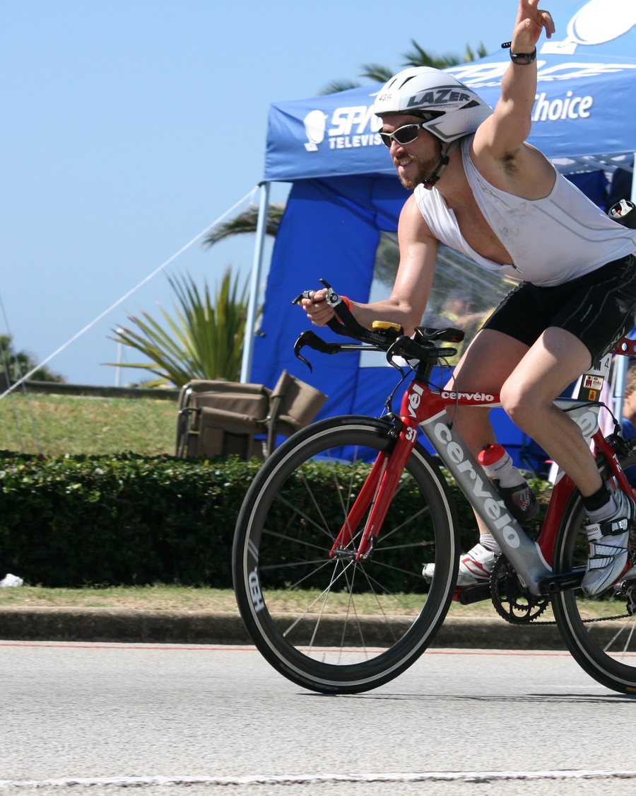 Josh on the bike leg of Ironman South Africa, waving to the crowd